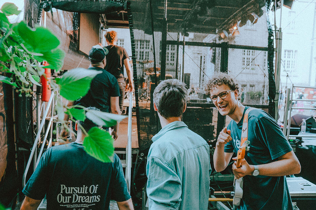 Paperthin Fleet – Backstage vor dem Konzert Mitglieder der Indie-Rock-Band Paperthin Fleet aus Münster unterhalten sich backstage neben einer Open-Air-Bühne.